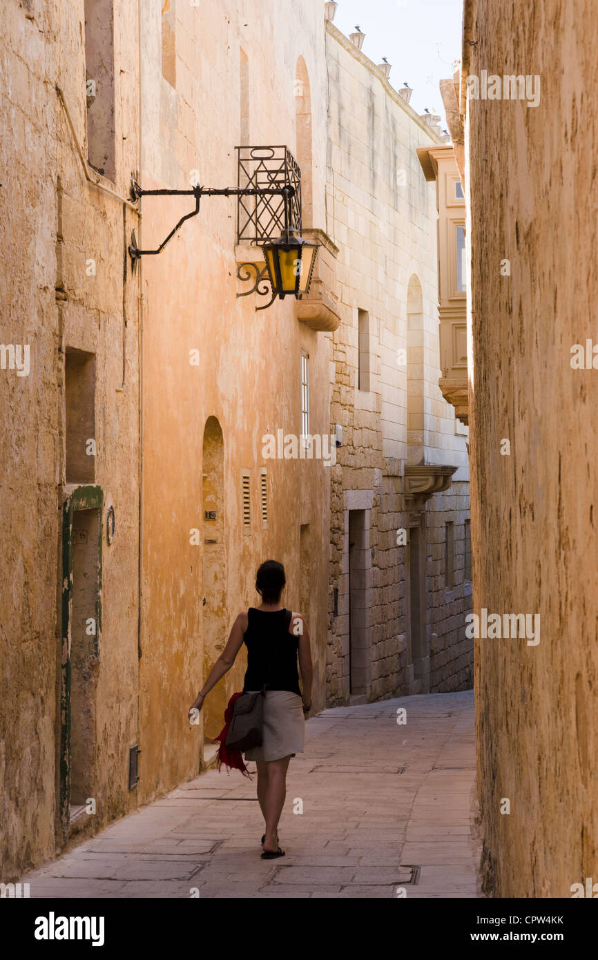 Young woman walking in narrow alley in historic city of Mdina, Malta Stock Photo