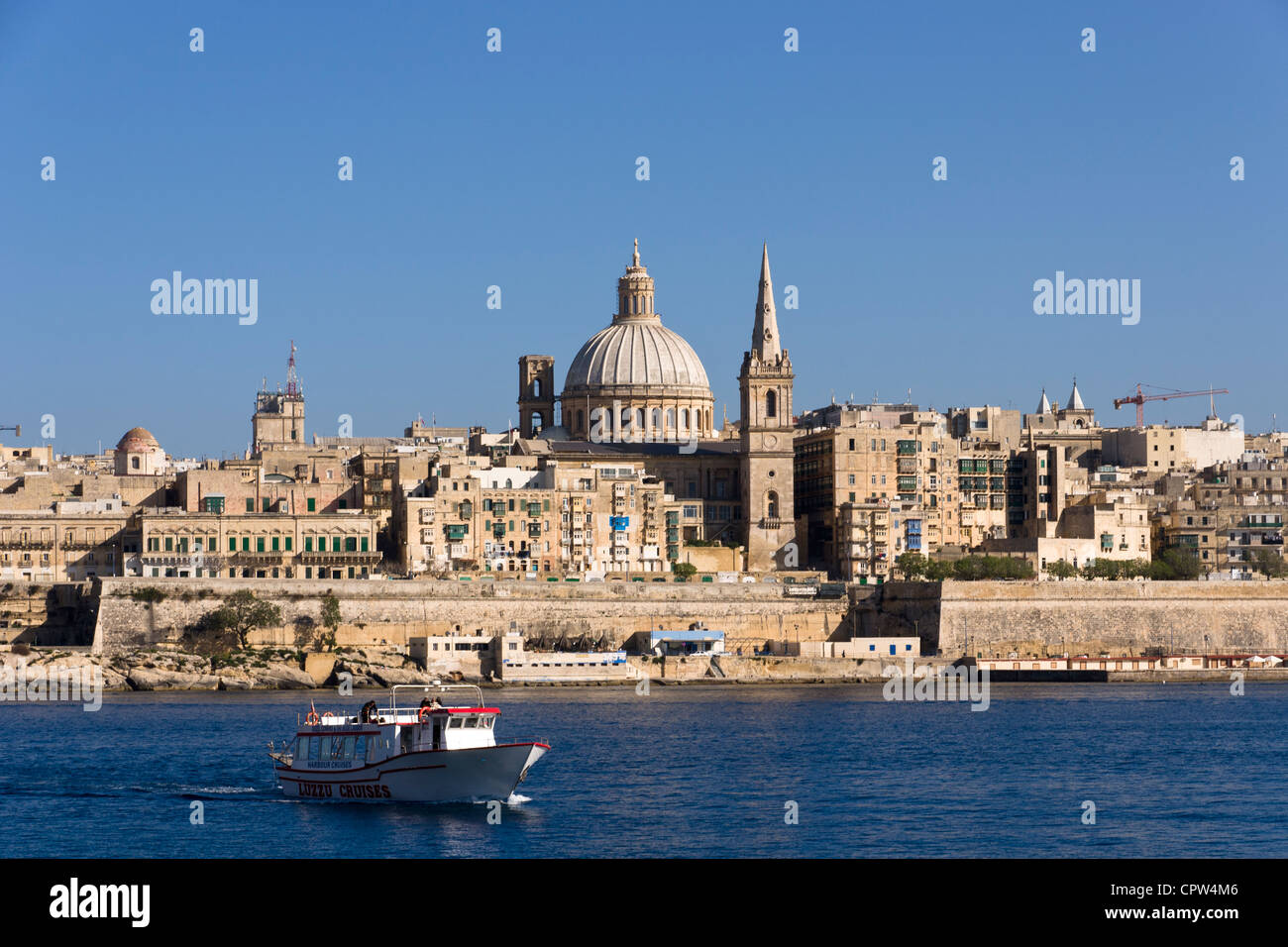 Tourist harbour cruise boat in front of Valletta skyline, Malta Stock Photo