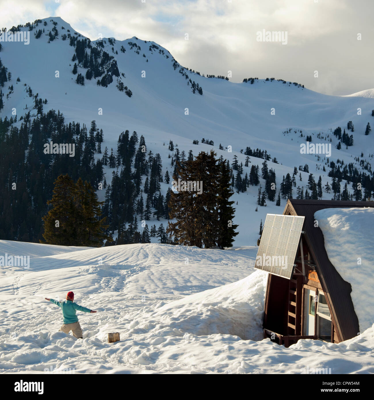 Cabin In The Mountains With Person Doing Yoga In Snow Outside