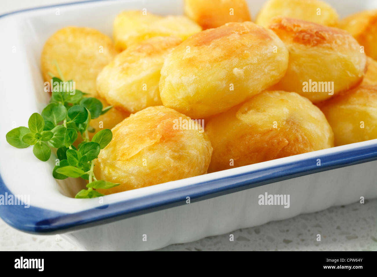Crunchy, golden roast potatoes, garnished with thyme, ready to serve. Stock Photo