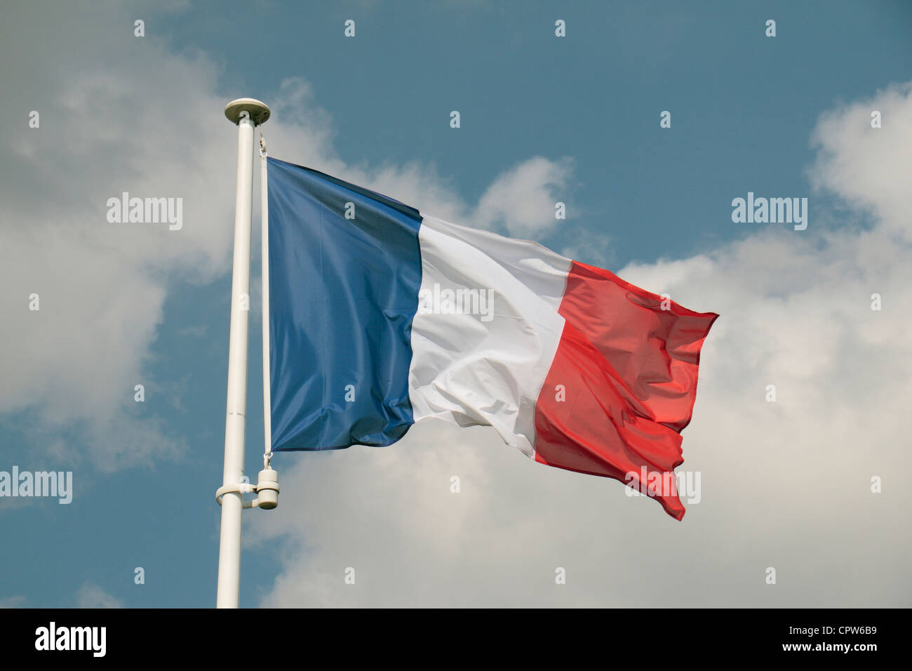 The French Tricolor against a blue, cloudy sky at the French National Cemetery at Buzy-Darmont, Lorraine, France. Stock Photo