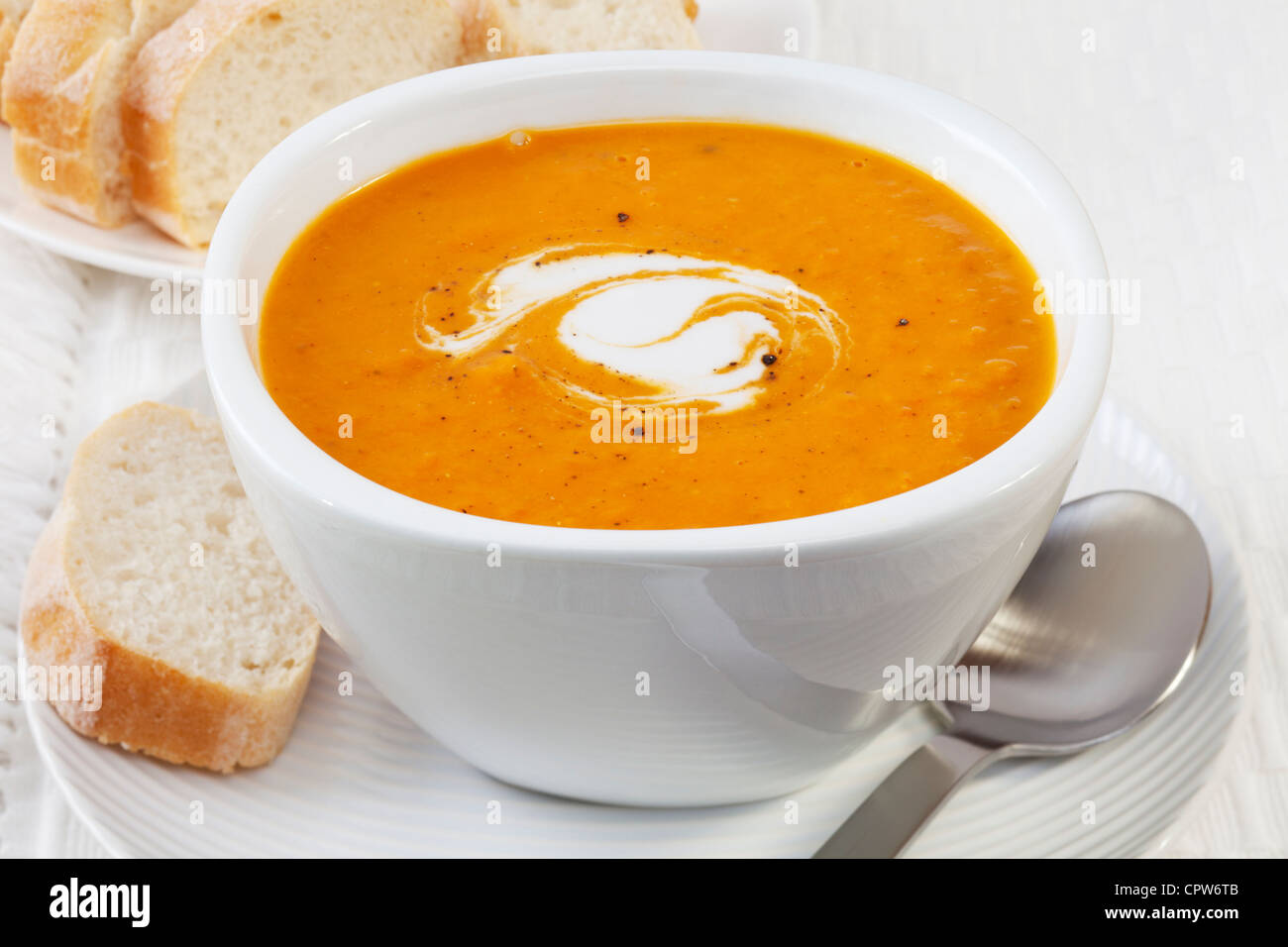 A bowl of spicy pumpkin soup, swirled with coconut cream. Stock Photo