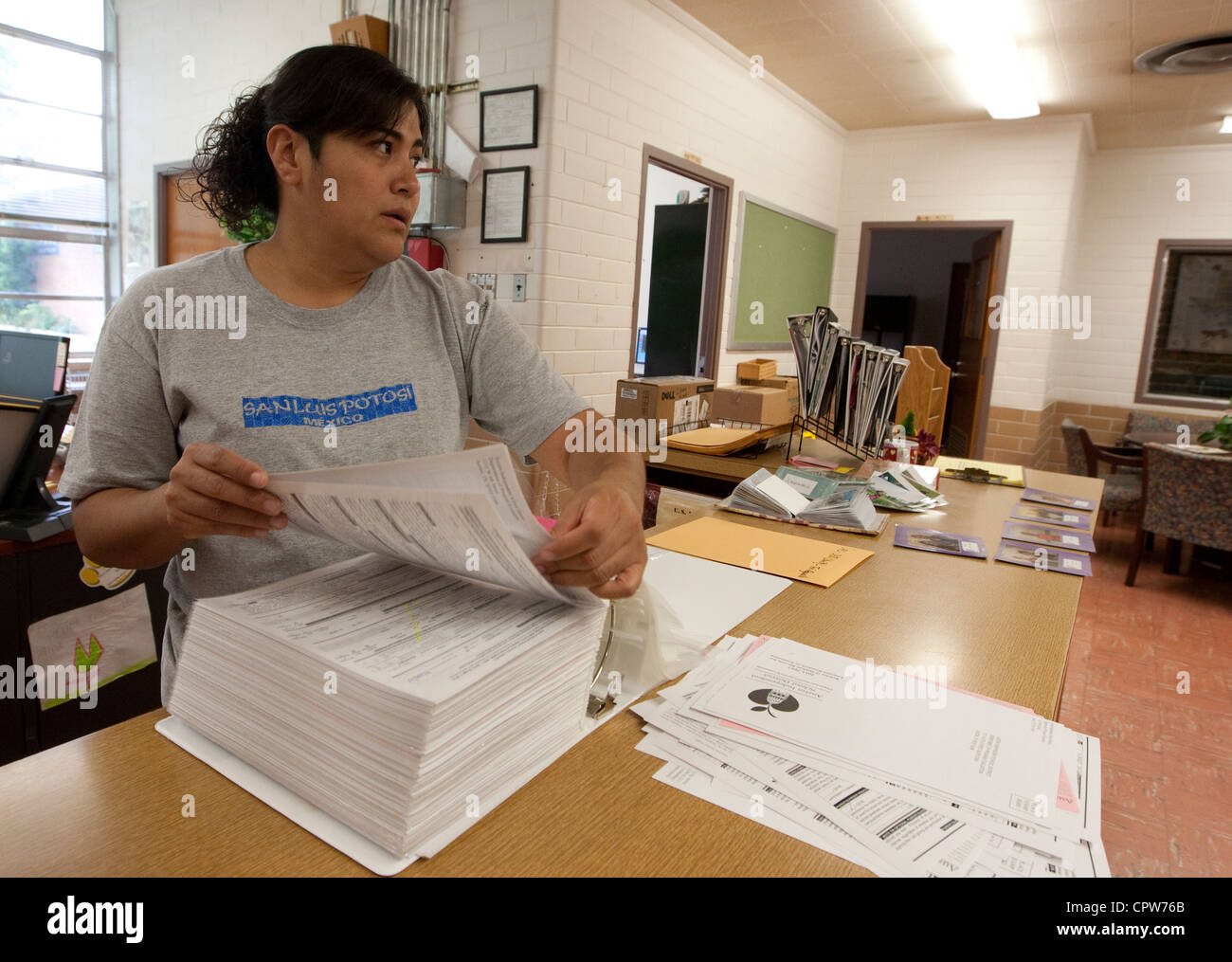 Hispanic female school office worker help pack up materials. The elementary school will become a charter school next school year Stock Photo