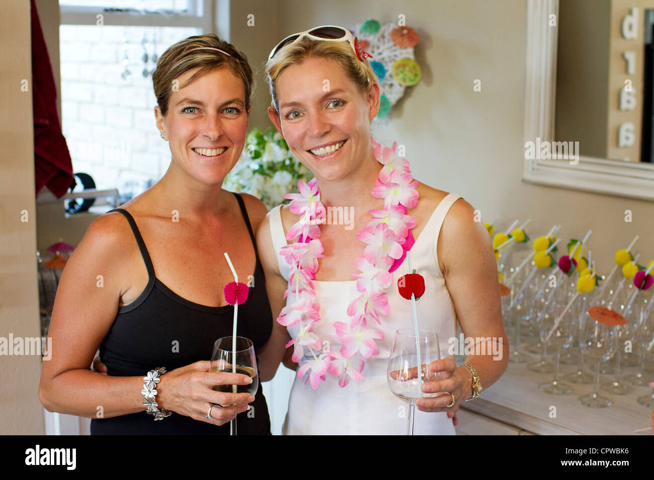 Two pretty party girls smiling with arms around each other Stock Photo ...