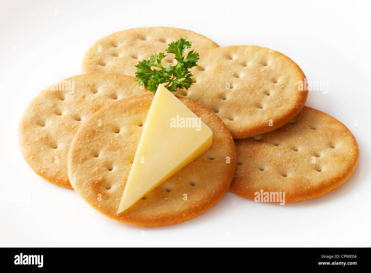 Classic snack, cheddar cheese and crisp crackers on a white plate garnished with parsley. Clipping path included. Stock Photo