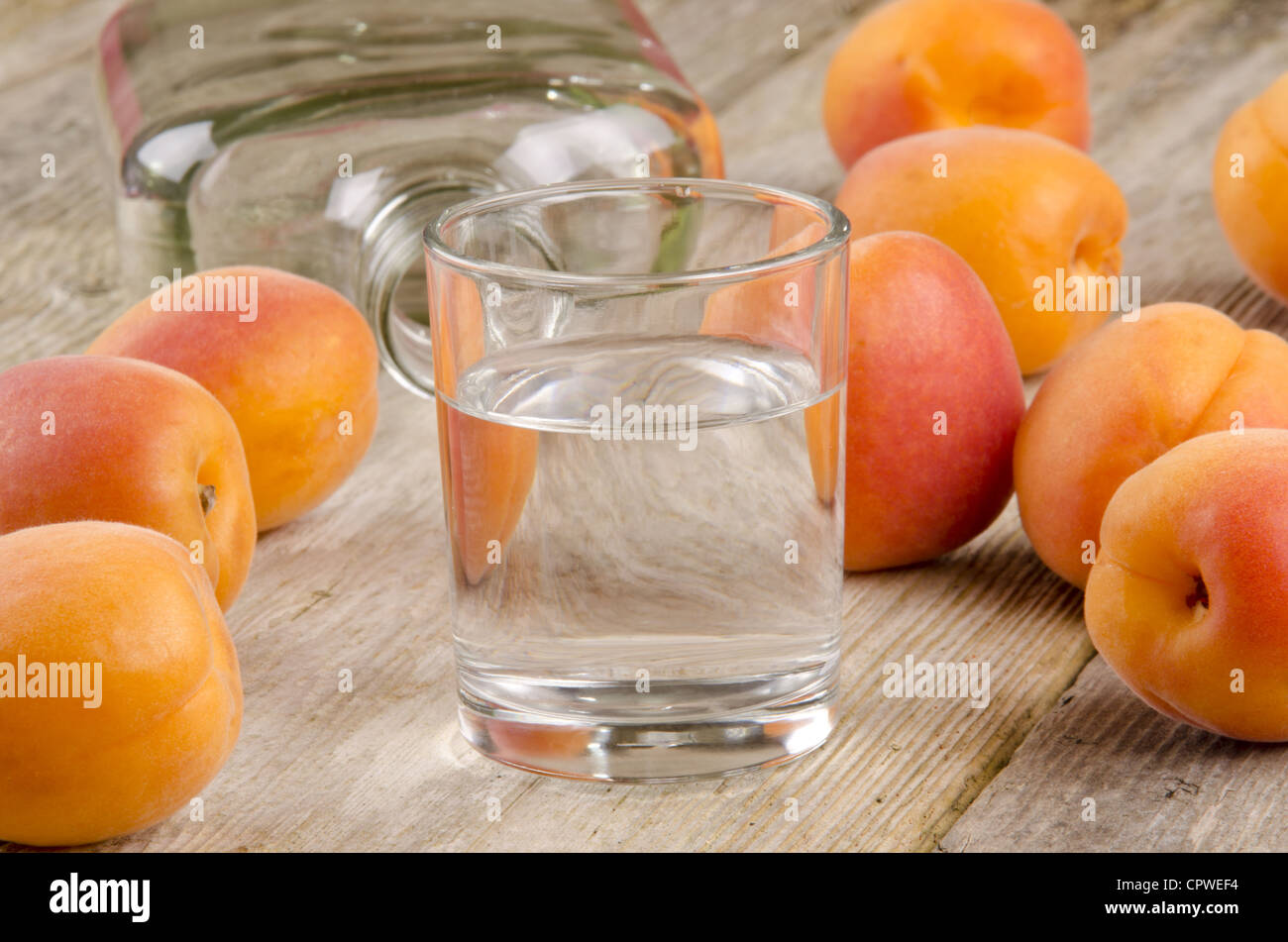 fruit brandy in a glass and fresh apricots in the background Stock