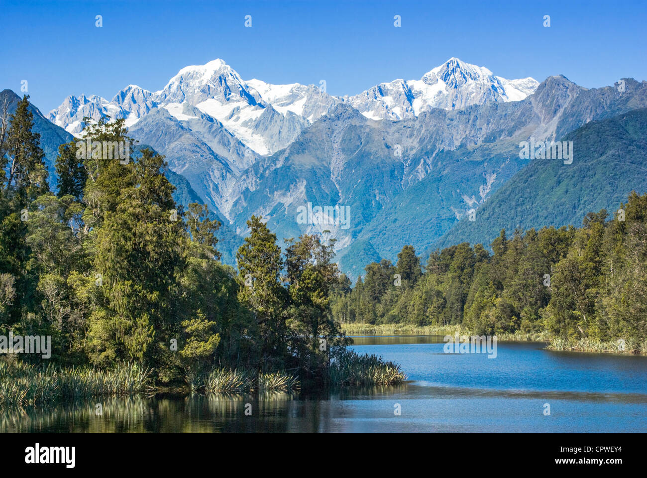 Lake Matheson with snow covered Mount Tasman and Mount Cook, New Zealand's highest mountain. Mount Cook is on the right. Stock Photo