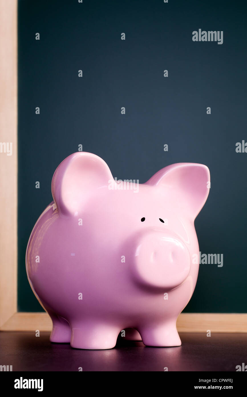 Pink piggy bank standing in front of blackboard, with space for your copy. Stock Photo