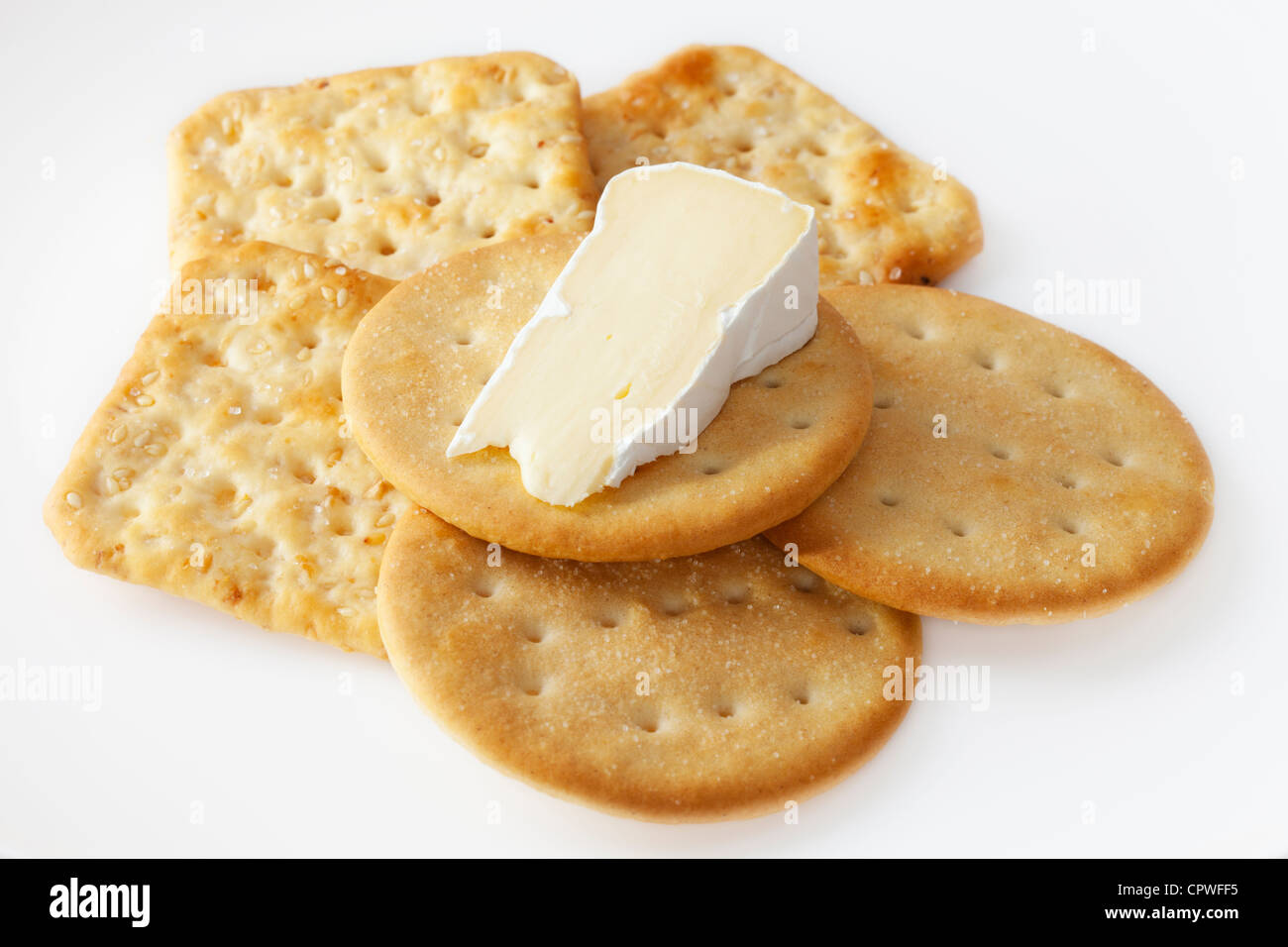 A wedge of camembert cheese on a white plate with crackers. Stock Photo