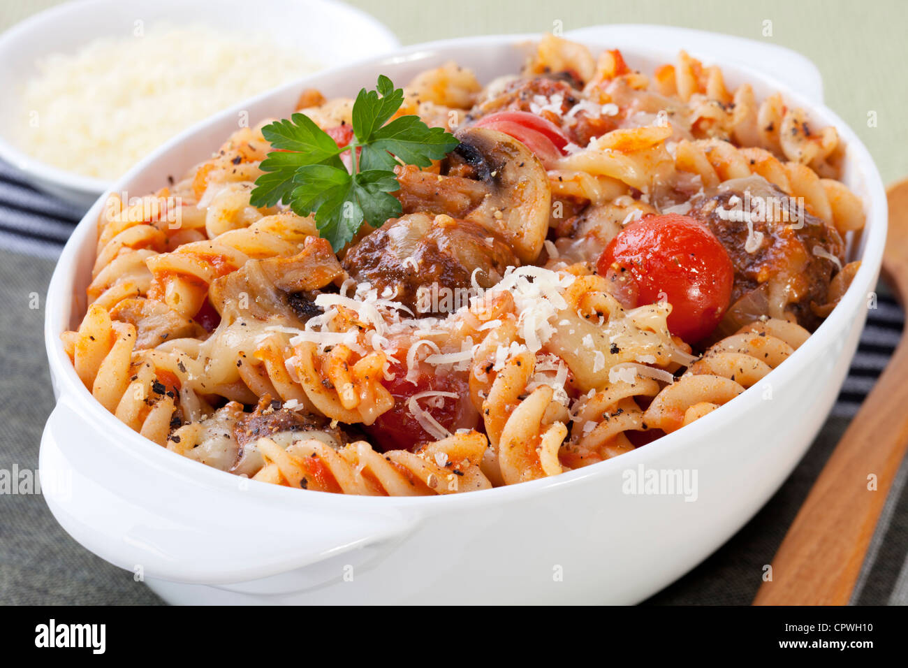 Pasta bake with meatballs, mushrooms and cherry tomatoes, in tomato sauce, with melting mozzarella. Stock Photo