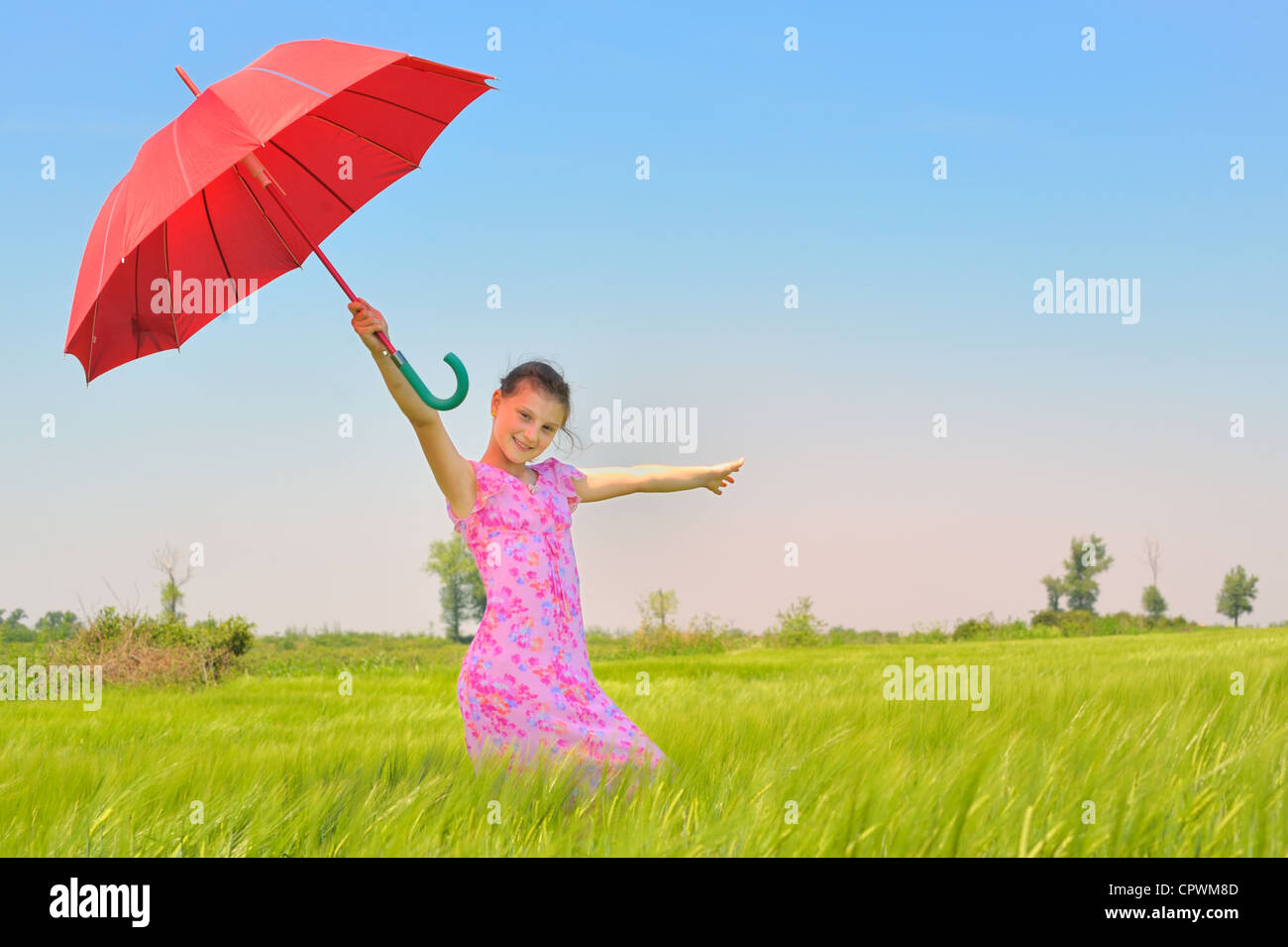 teenage girl with red umbrella in wheat field Stock Photo