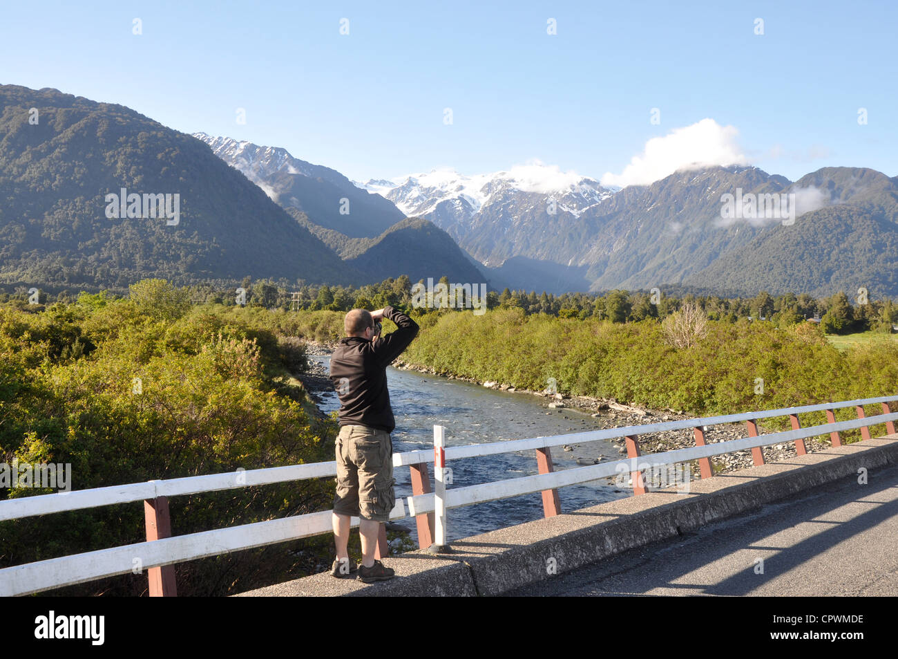Tourist taking photo of mountains near Franz Josef, South Island, West Coast, New Zealand Stock Photo
