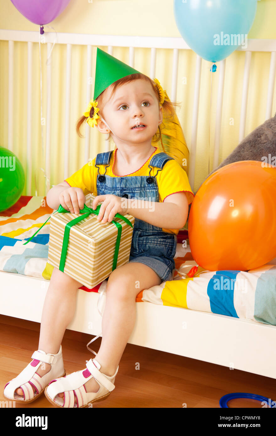 Little girl with present sitting on the bed on her second birthday Stock Photo