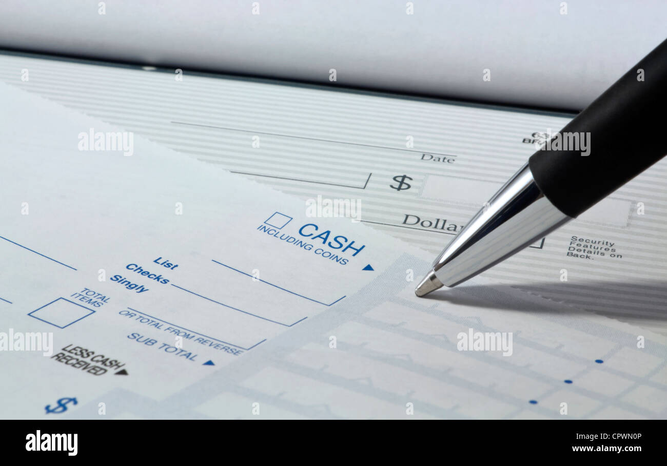 Close up of pen filling out a personal banking deposit slip with check in background and copy space. Stock Photo