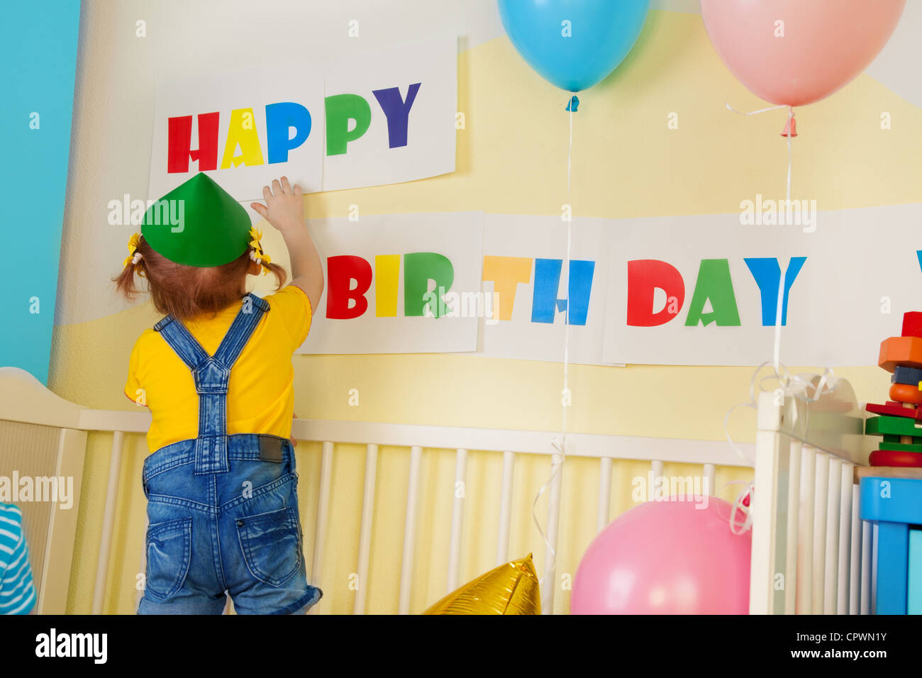 Little girl prepare for birthday party hanging a birthday sign Stock