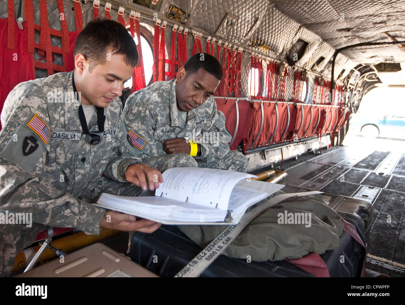 members of the United States Army in uniform review information inside a military aircraft for emergency disaster relief CH47 Stock Photo