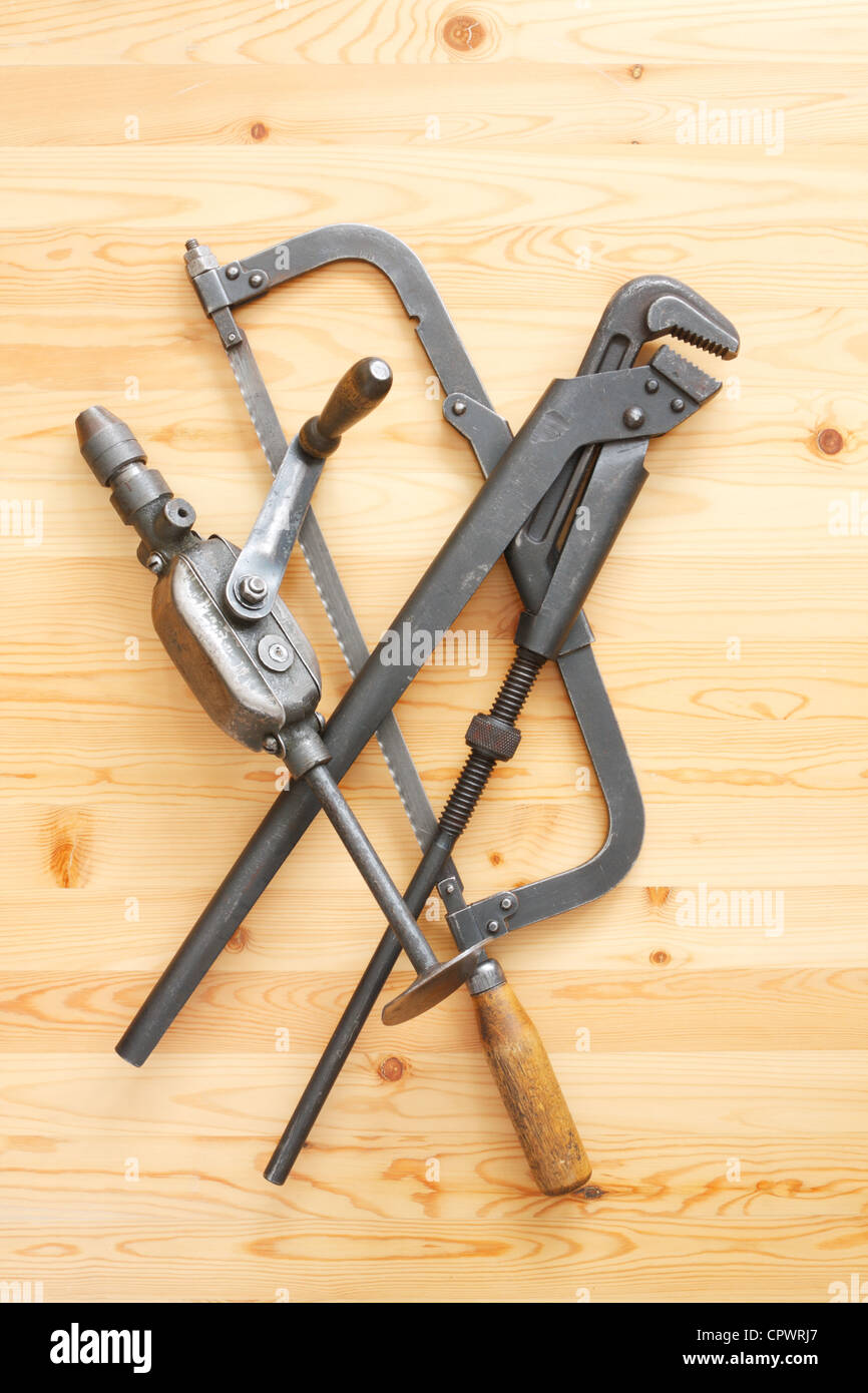 Hacksaw, adjustable spanner and drill on the wooden surface Stock Photo
