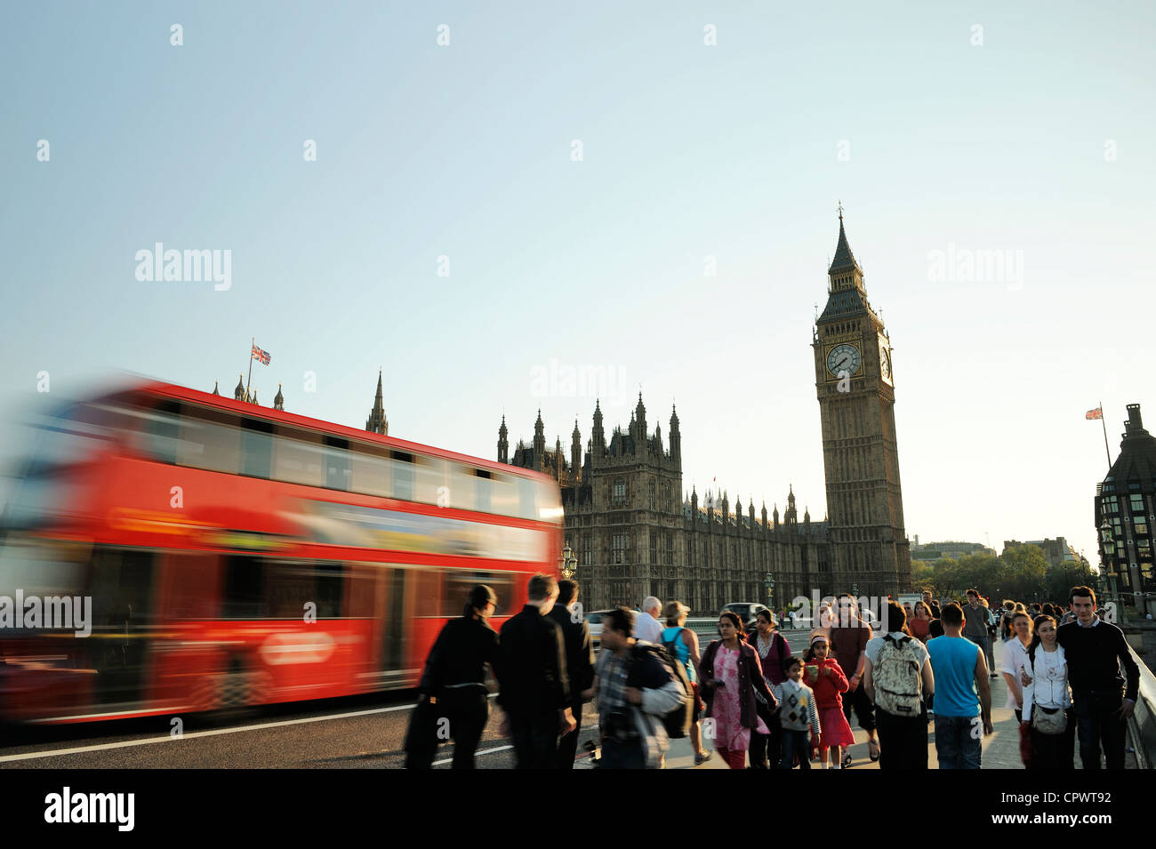 Crowds of people and a red London bus cross Westminster bridge in front of Big Ben Stock Photo
