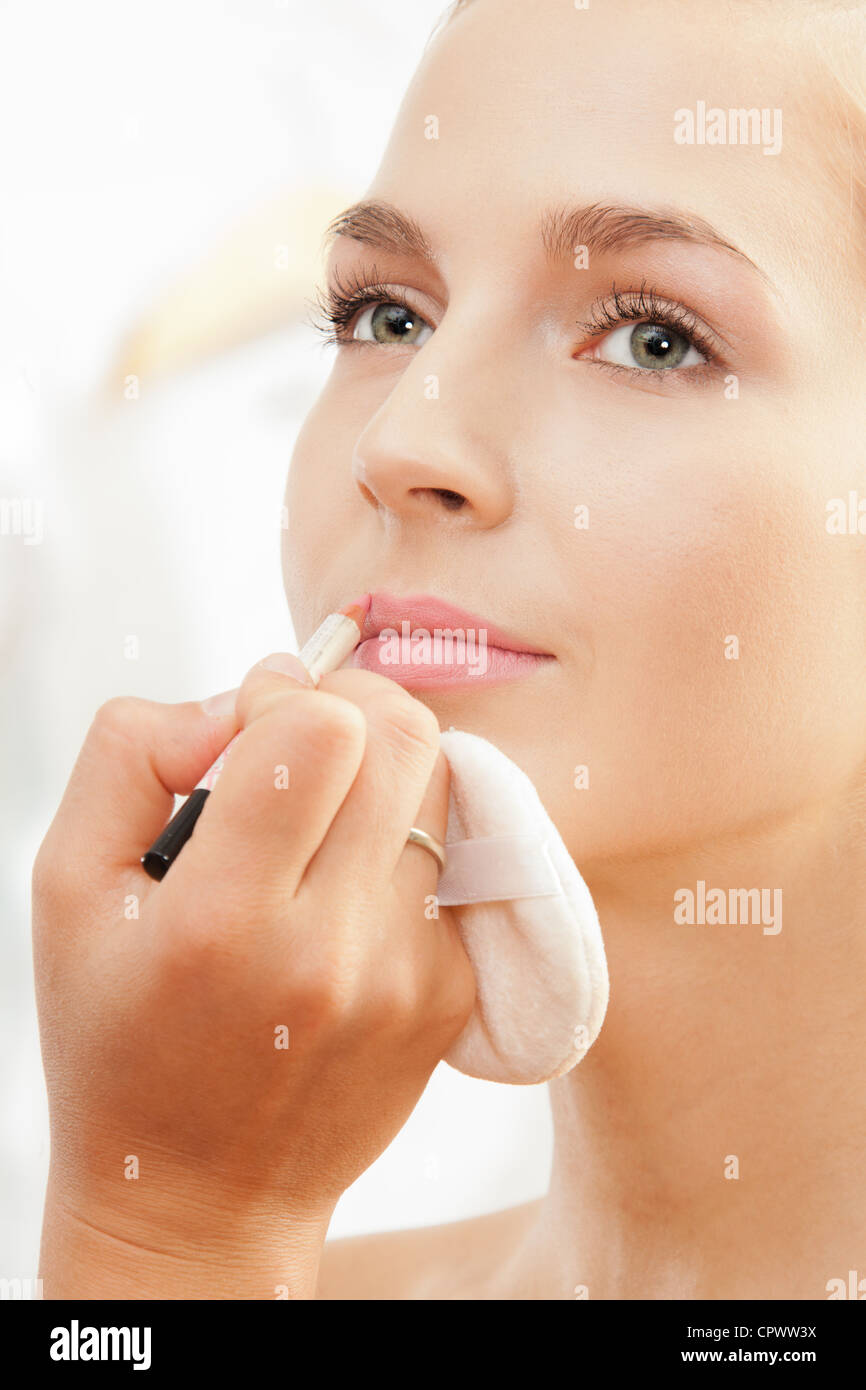 Closeup of makeup artist working defining lips shape with lip pencil