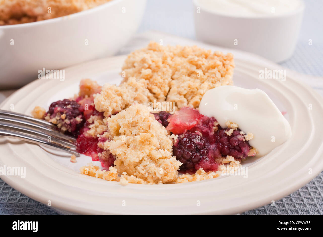 Home baked blackberry and apple crumble with a dollop of Greek yoghurt. Making the most of juicy autumn fruits. Stock Photo