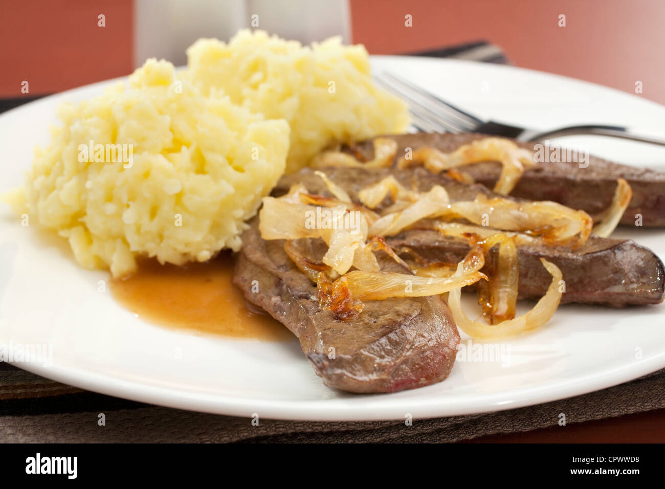 Lamb's liver with caramelised onions and mashed potato on a white plate. Stock Photo
