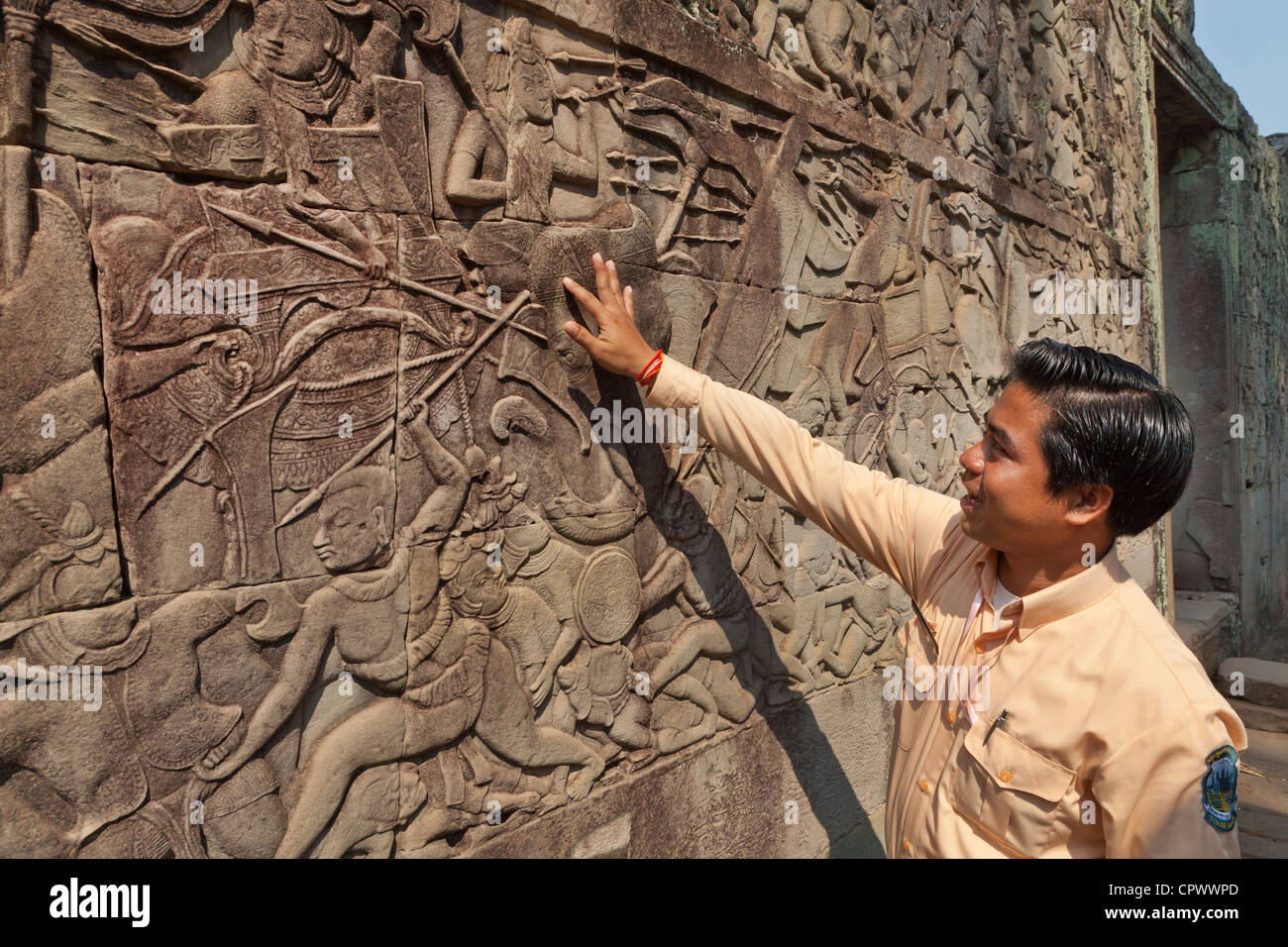 Tour guide explaining the history of carved stone panels, Ta Prohm, Angkor, Siem Reap Province, Cambodia. Stock Photo