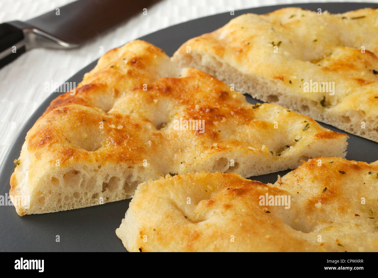 Pizza bread with garlic and herbs, on a platter with one slice cut