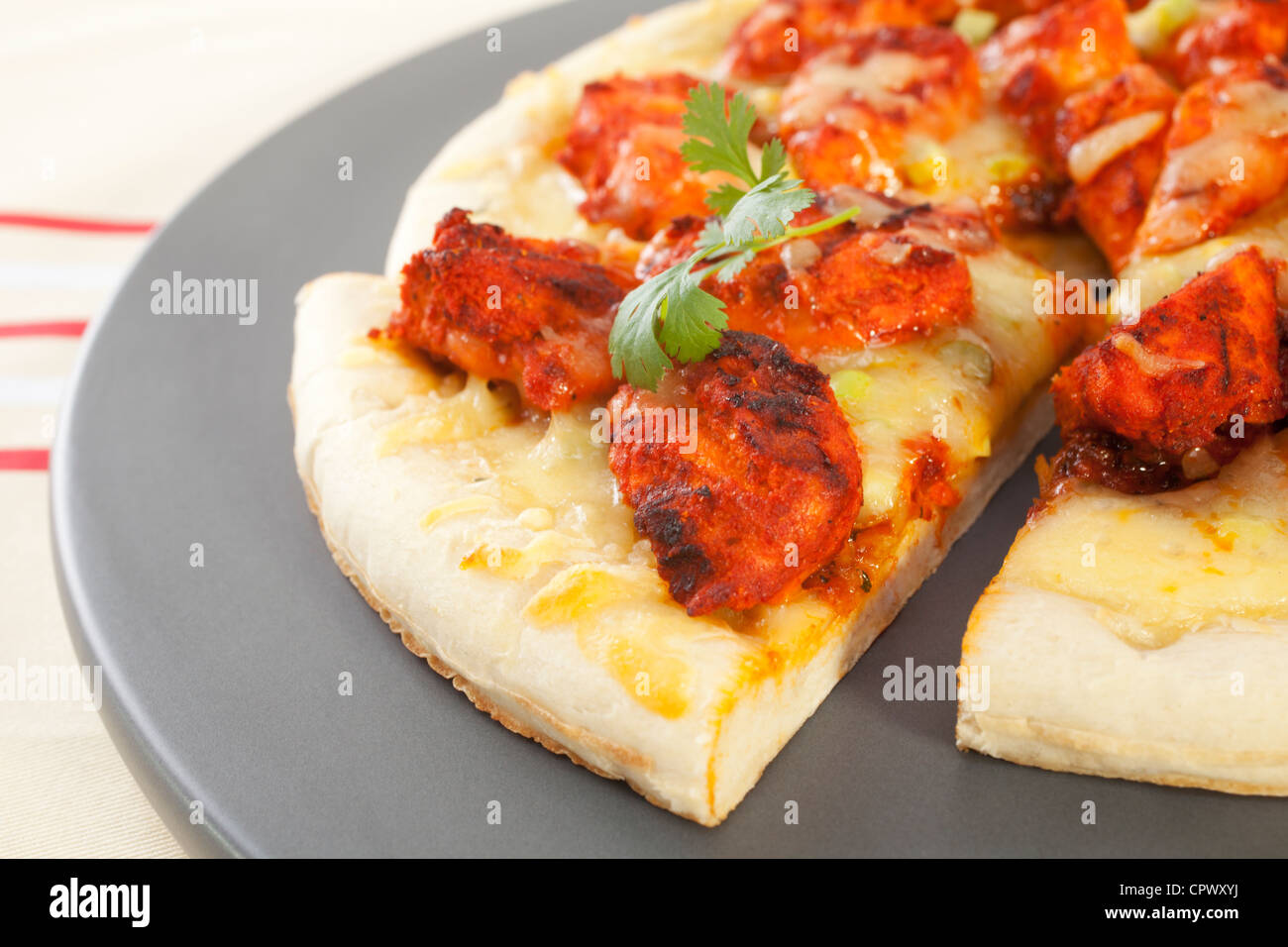 chicken tikka pizza, topped with mozzarella and coriander. Stock Photo