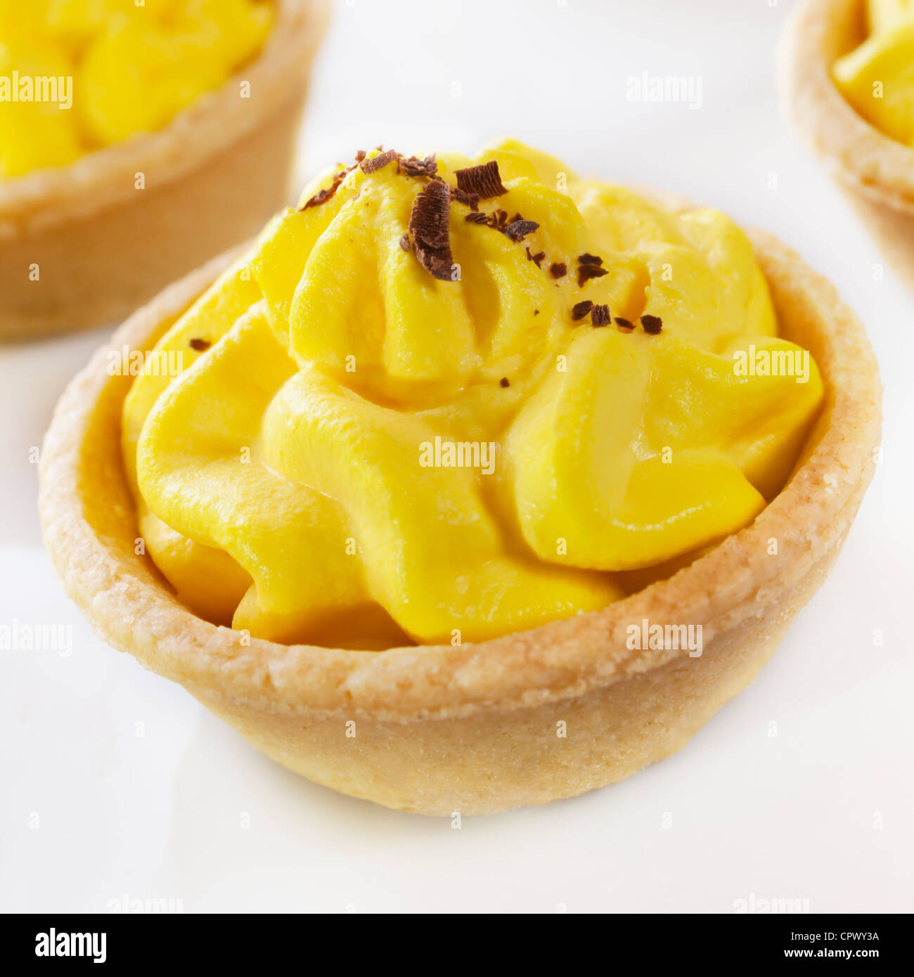 Pastry shells filled with lemon flavoured cream, topped with chocolate. Stock Photo