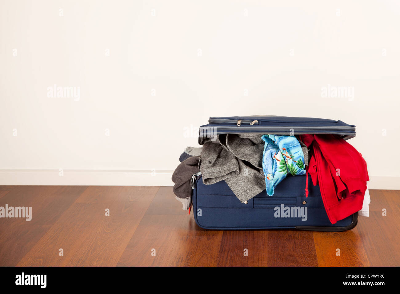 A suitcase overflowing with clothes Stock Photo