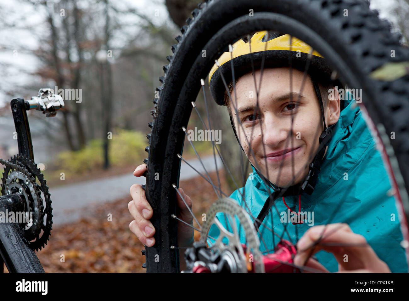 Young man fixing bicycle wheel in forest Stock Photo