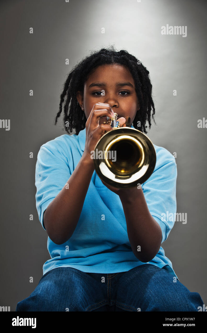 Portrait of black teenage boy playing trumpet, studio shot Stock Photo