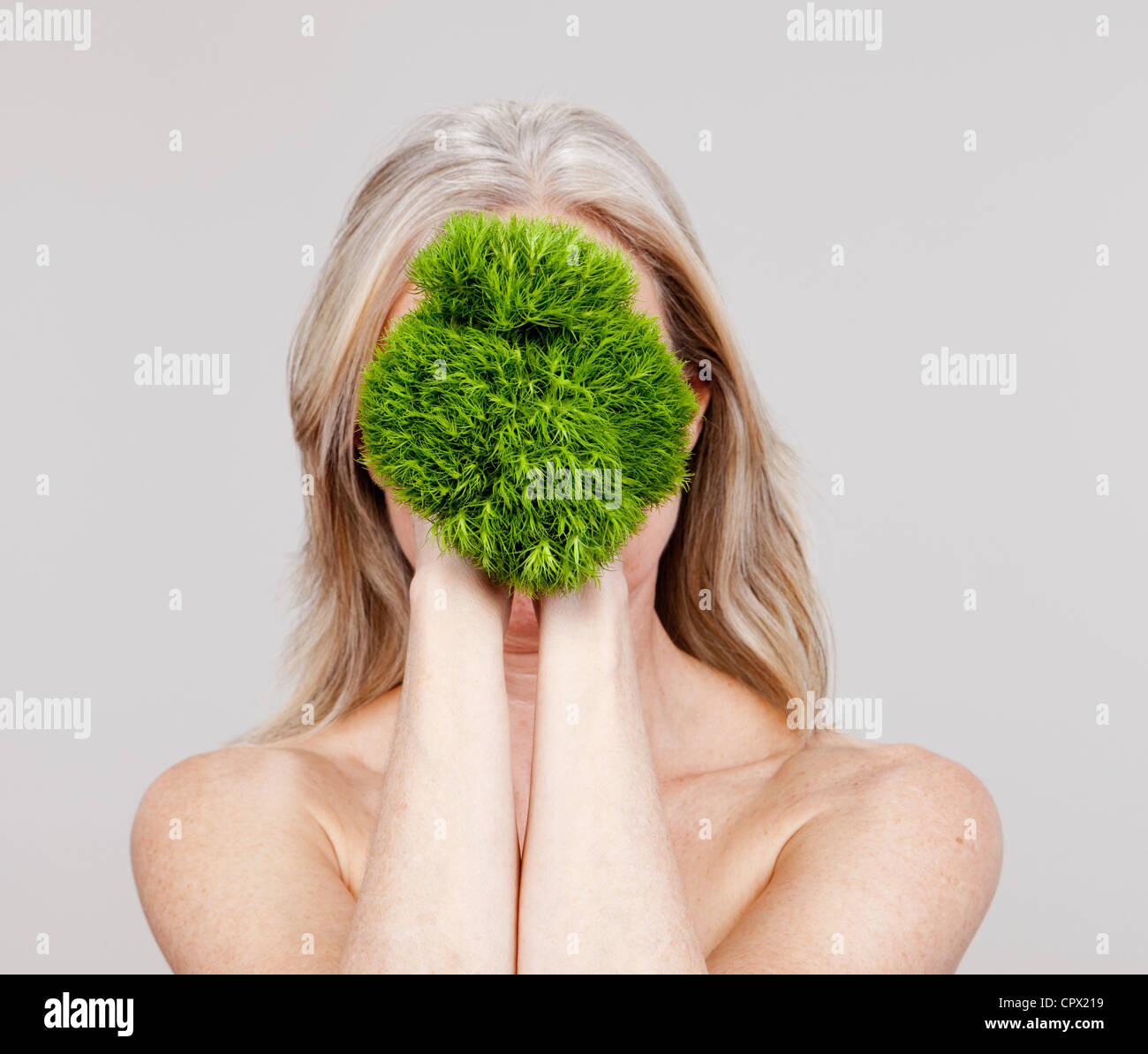 Mature woman holding plant in front of face Stock Photo