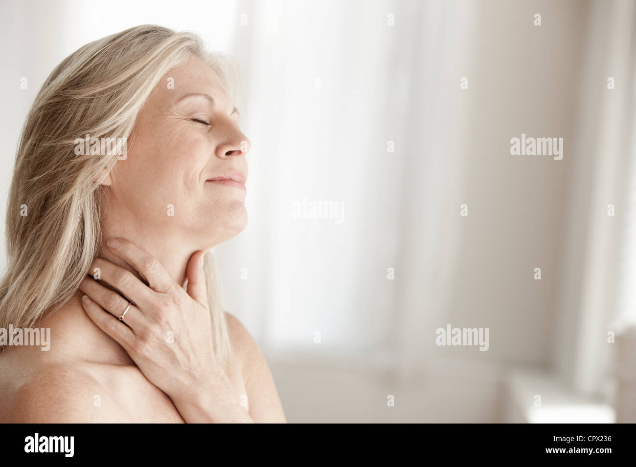Mature woman touching neck Stock Photo