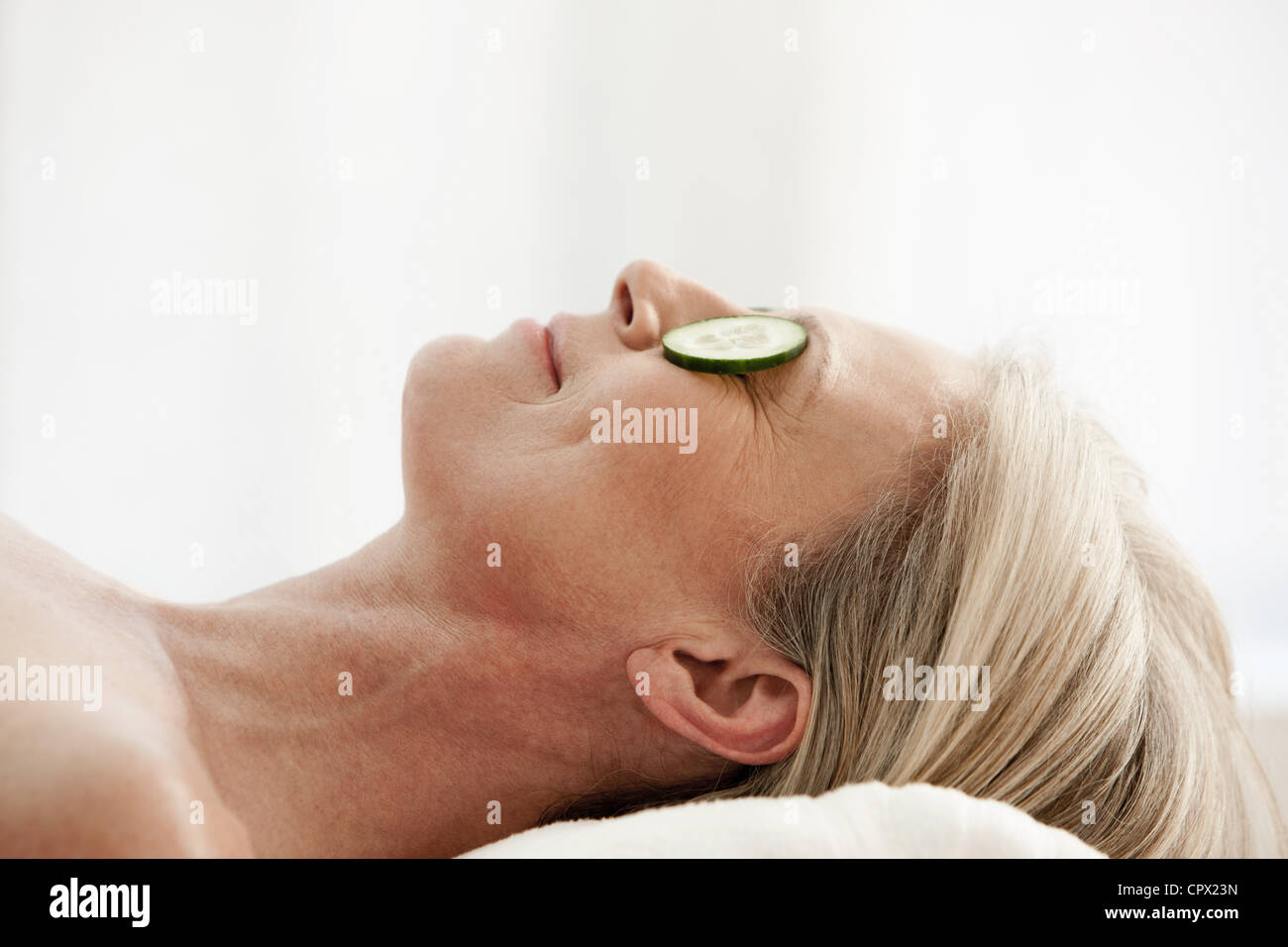 Mature woman relaxing with cucumber slices over eyes Stock Photo