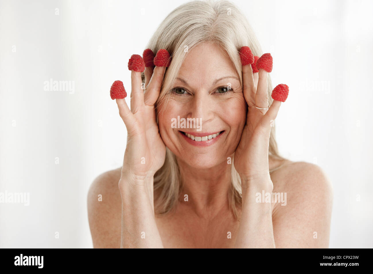Mature woman wearing raspberries on fingers Stock Photo