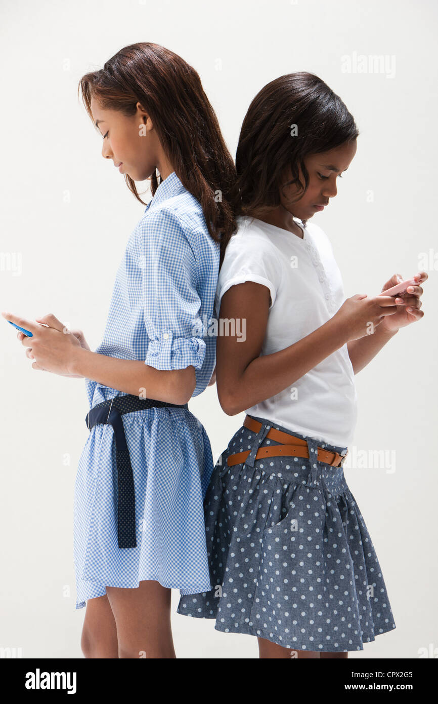 African American sisters using cellphones, studio shot Stock Photo