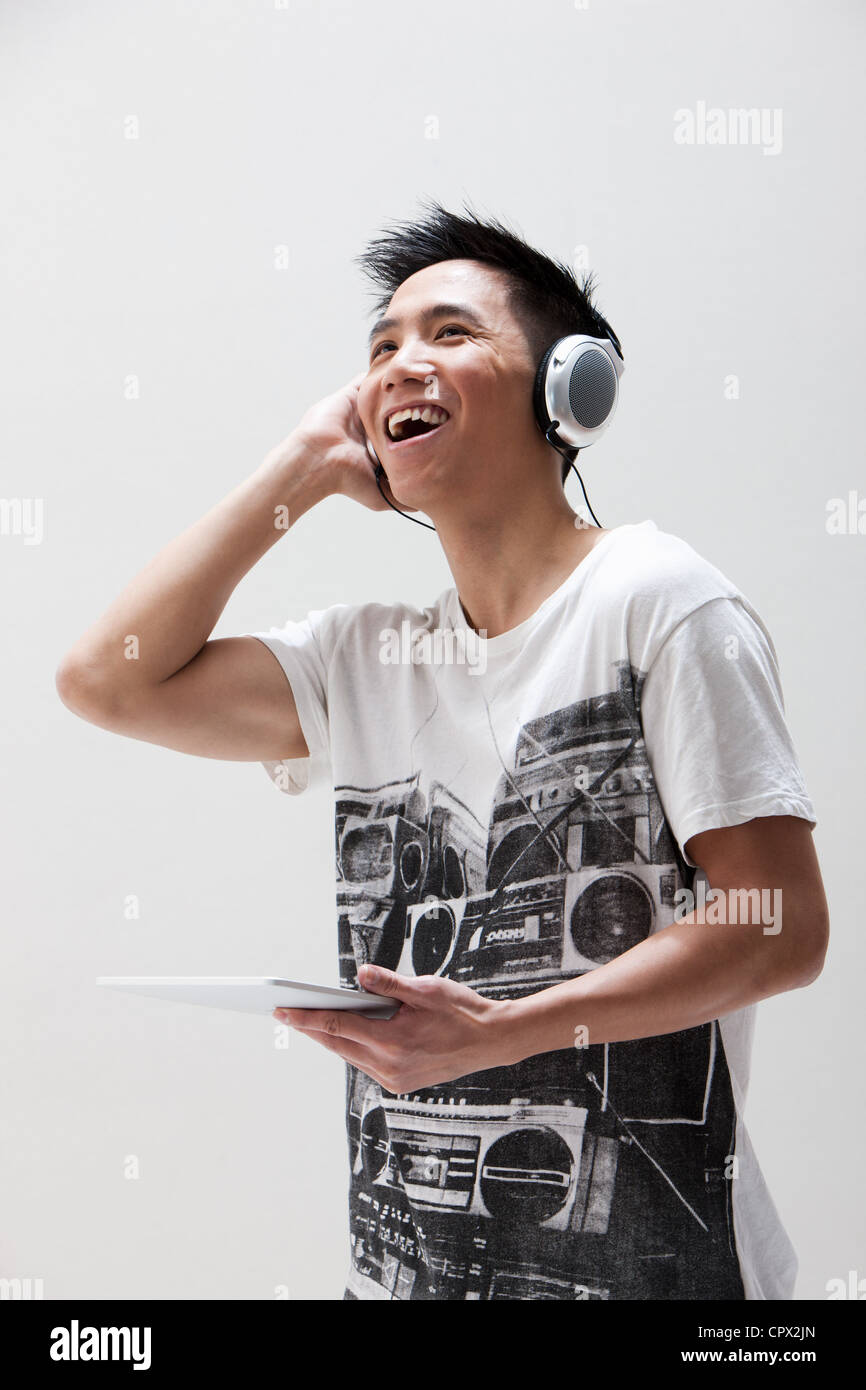 Young Asian man using digital tablet with headphones, studio shot Stock Photo