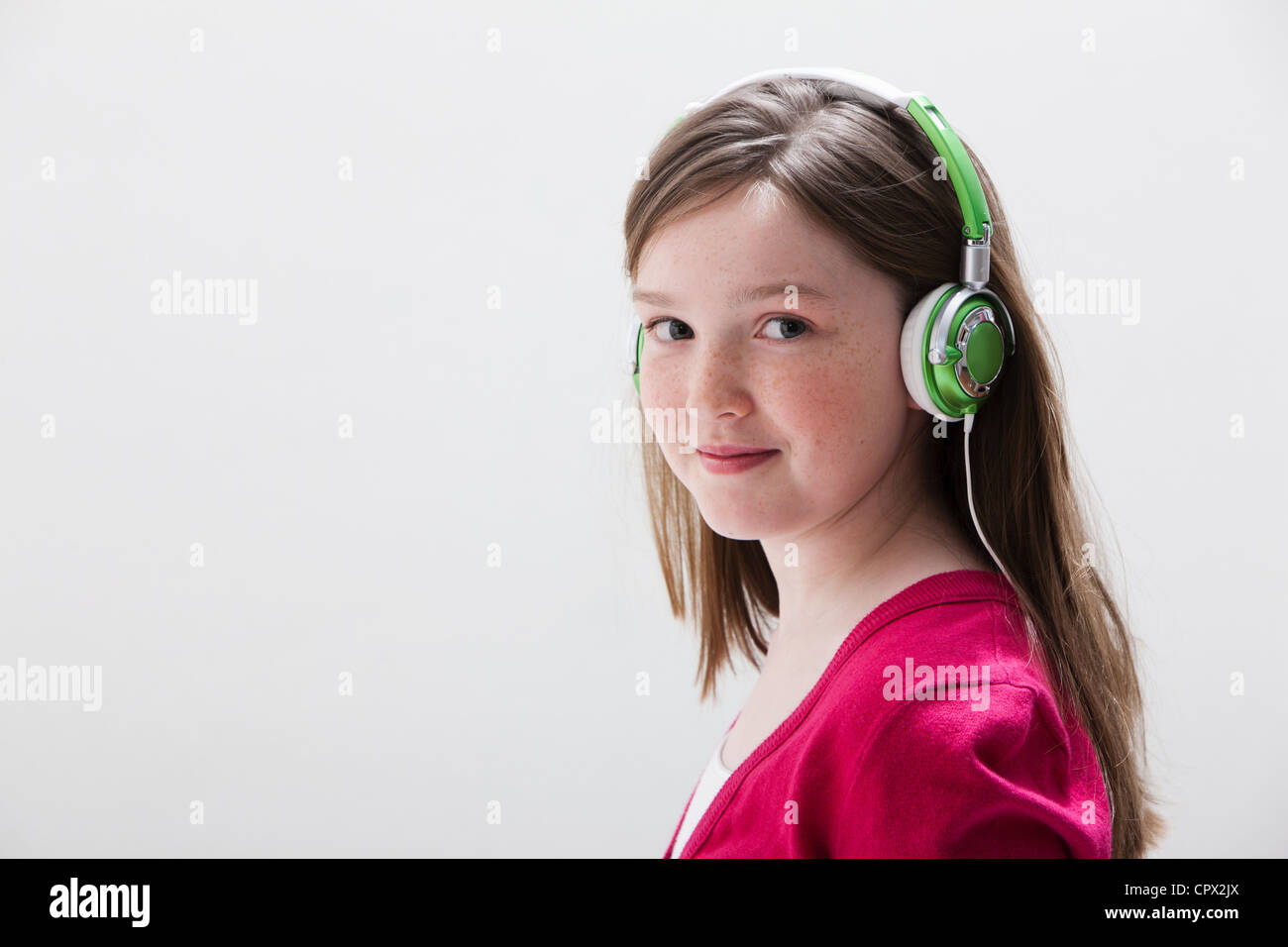 Girl in red wearing headphones, studio shot Stock Photo
