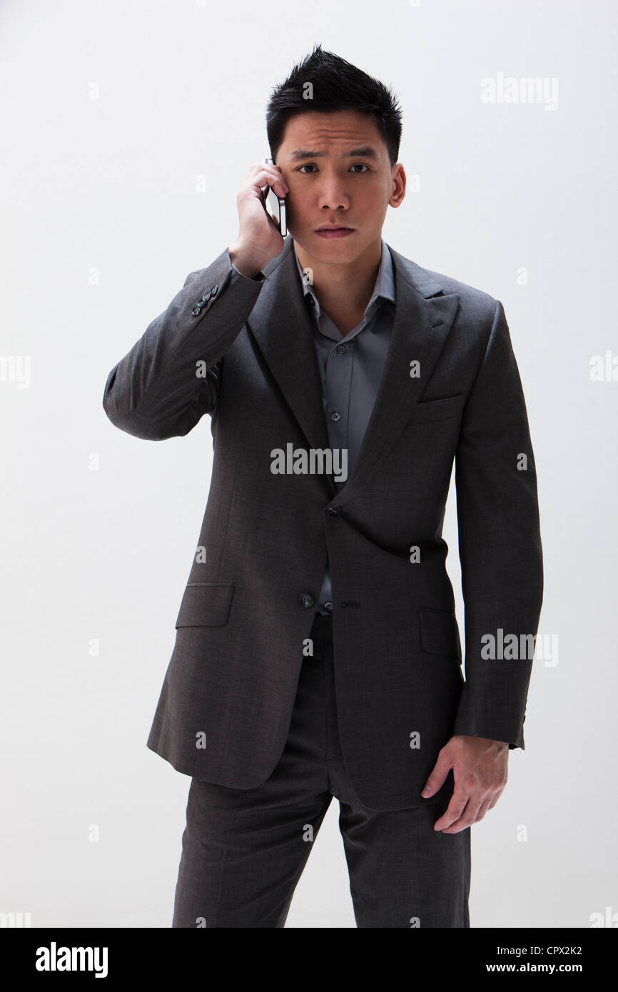 Young Asian businessman using cellphone, studio shot Stock Photo