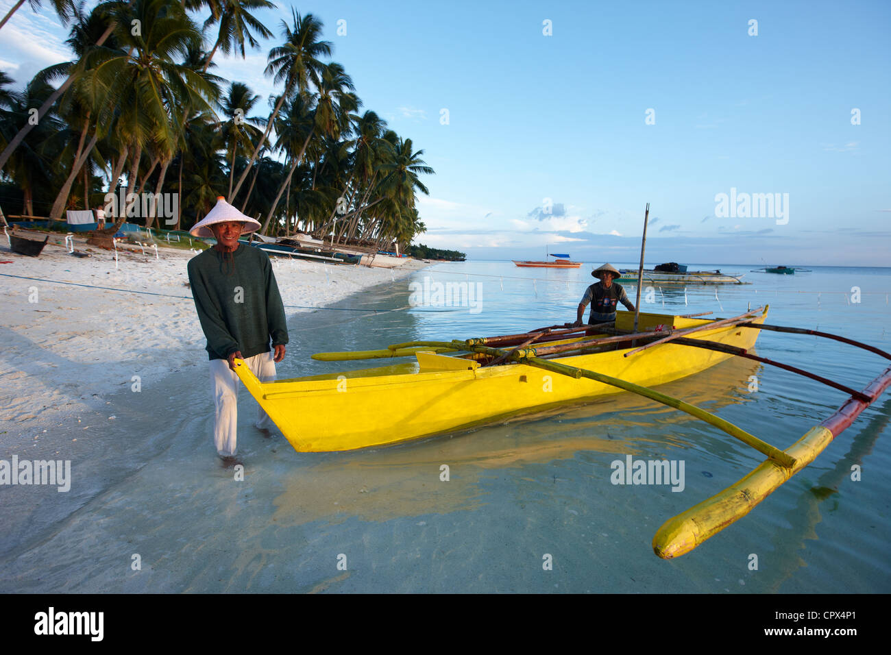 fisherman launching a boat on San Juan Beach at dusk, Siquijor, The Visayas, Philippines Stock Photo