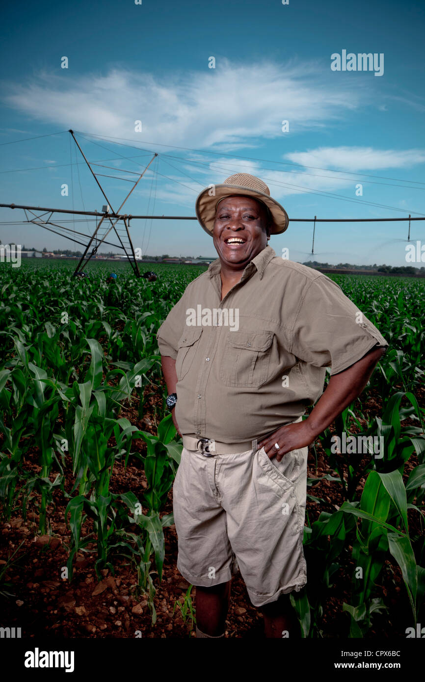 Black farmer stands smiling in a crop field with irrigation systems in the  background Stock Photo - Alamy