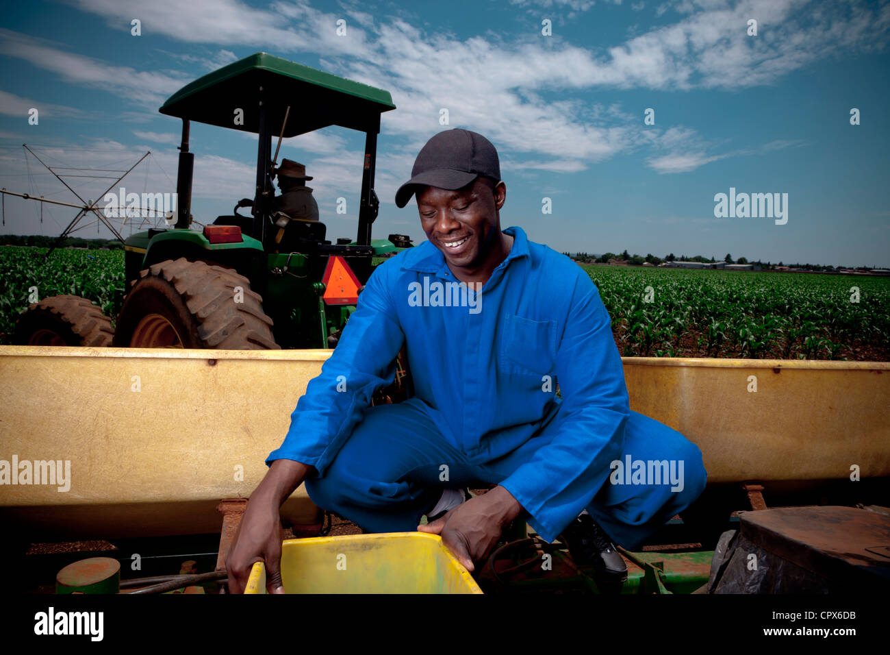 Black farm worker working, with a tractor in the background Stock Photo