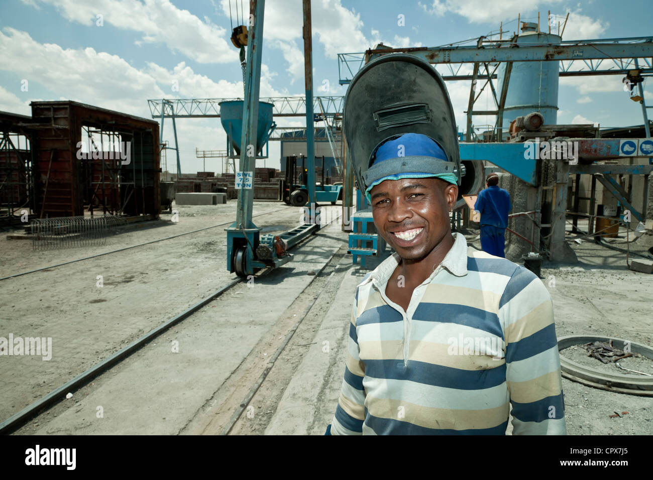 Black factory worker stands in construction yard smiling at camera Stock Photo