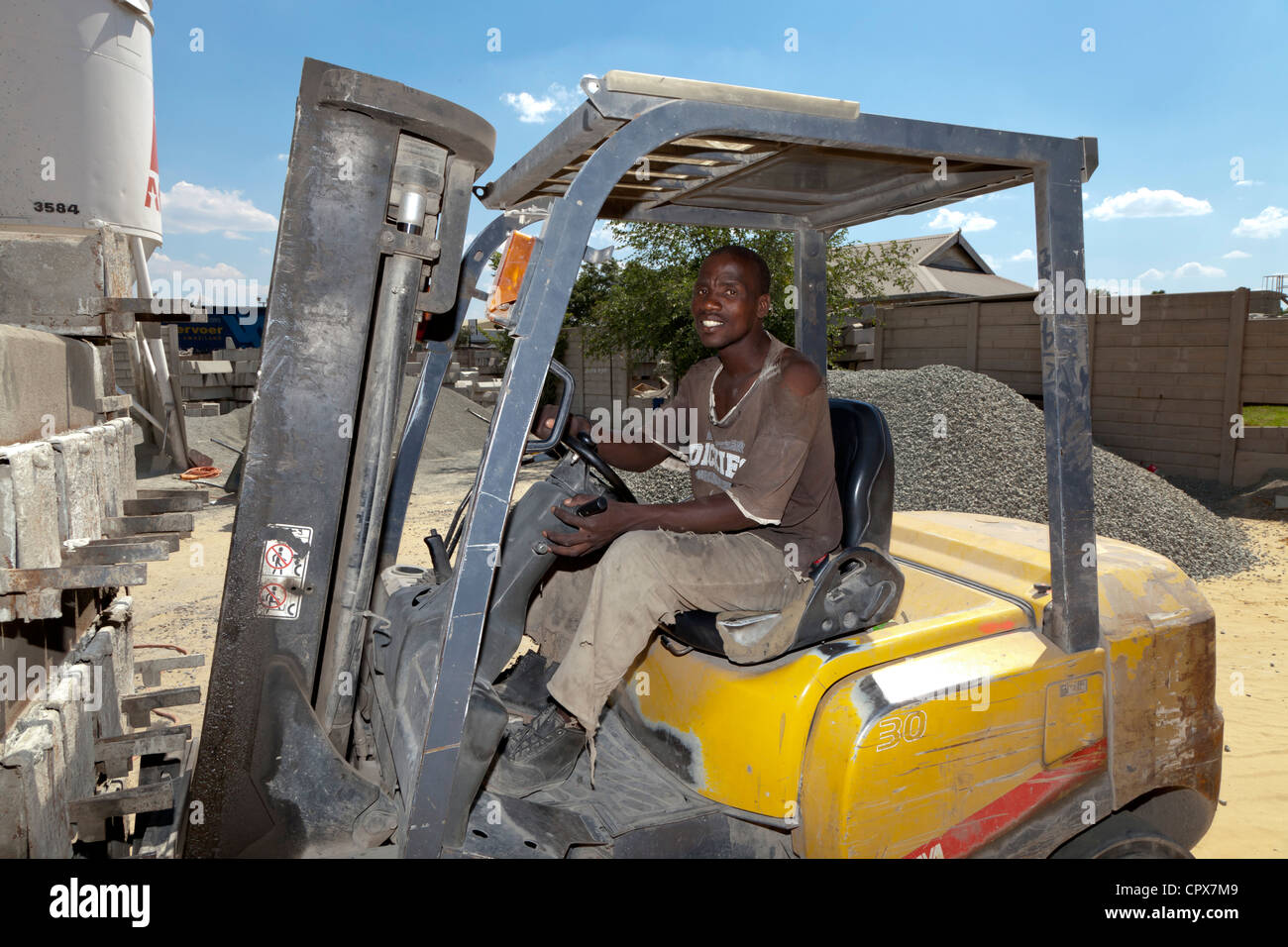 African construction worker drives a forklift in a construction yard