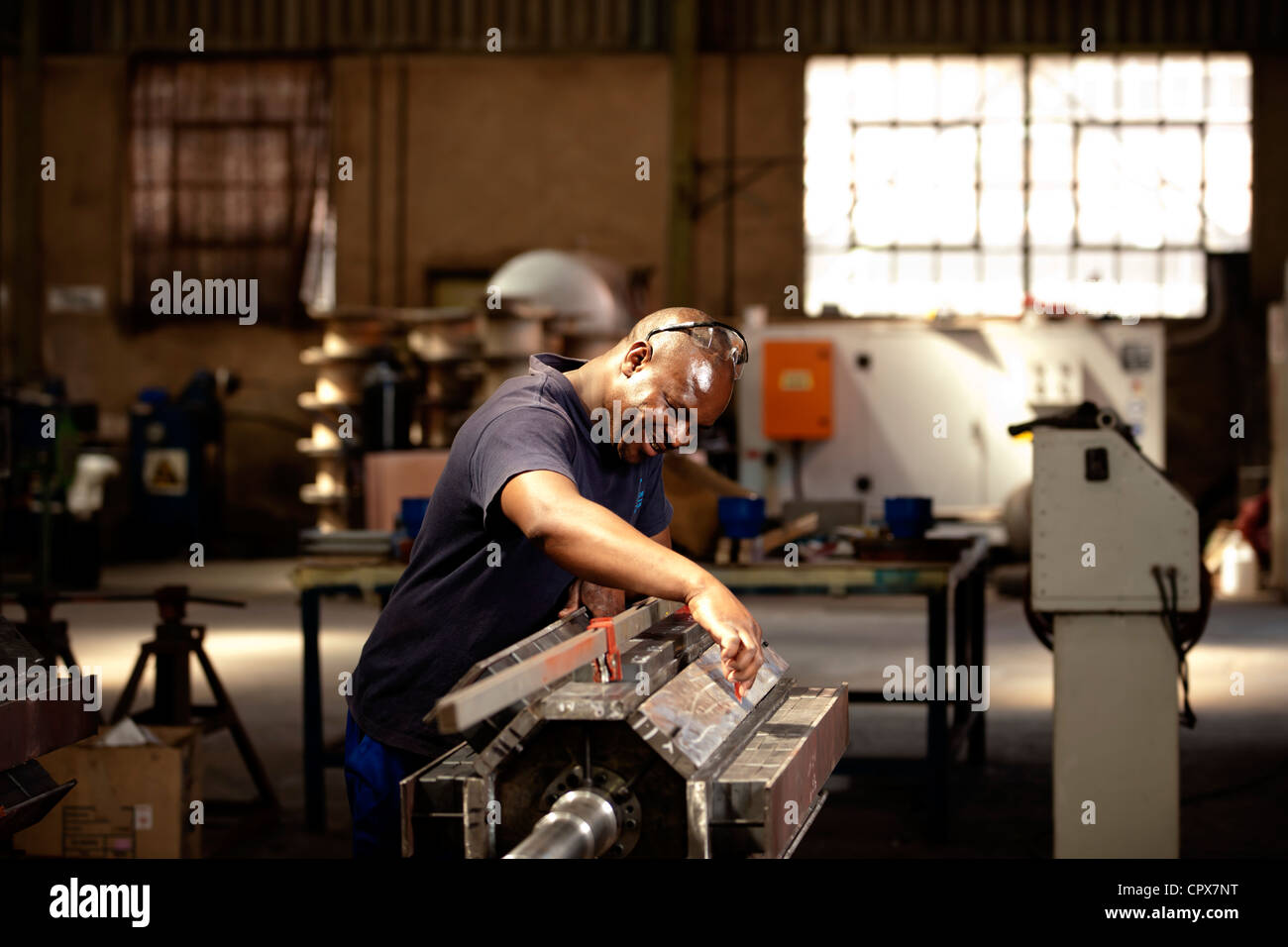 Factory worker attaching charged magnets to industrial magnet in magnet factory, Gauteng, South Africa Stock Photo
