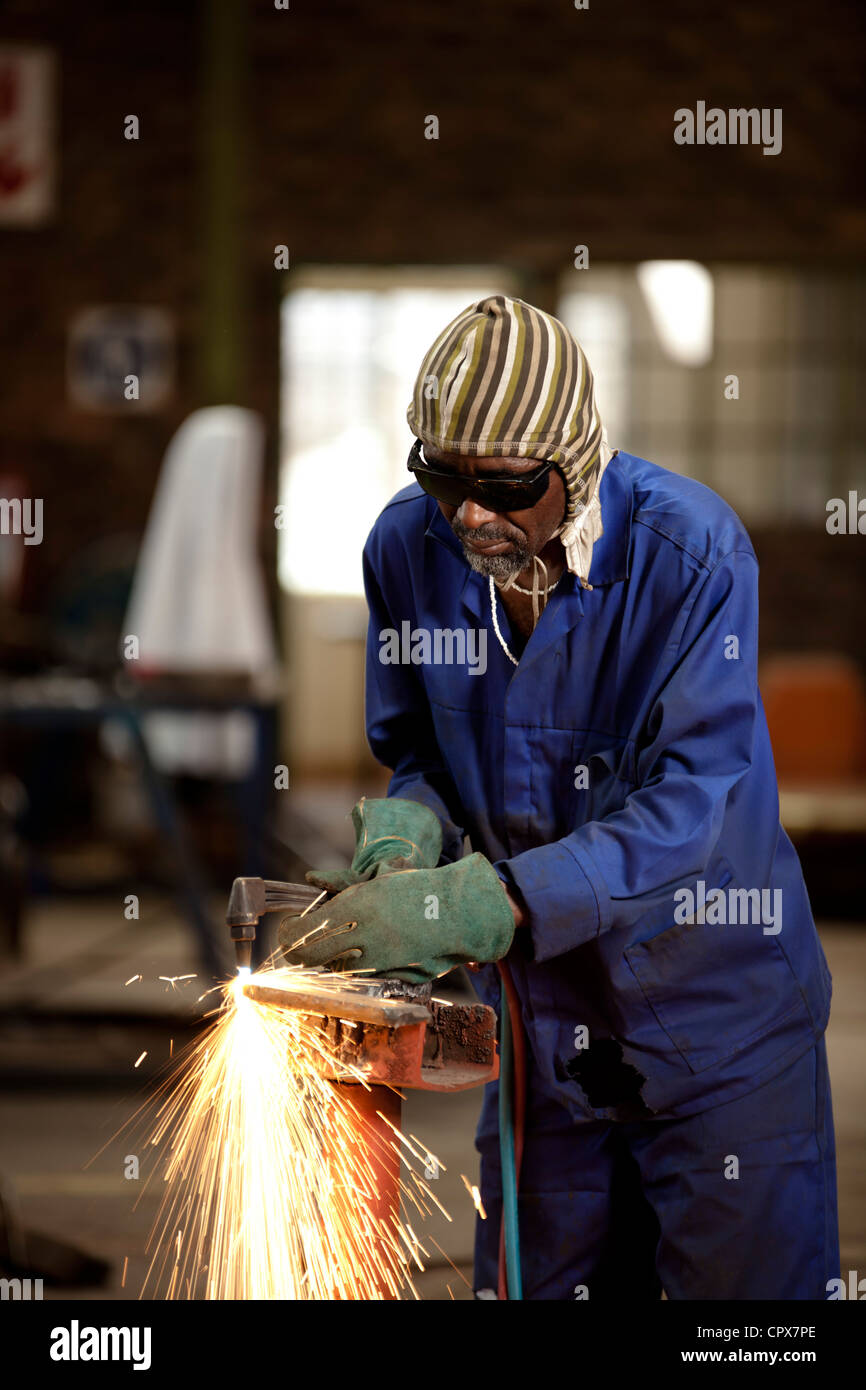 Factory worker operating blow torch, magnet factory, Gauteng, South Africa Stock Photo