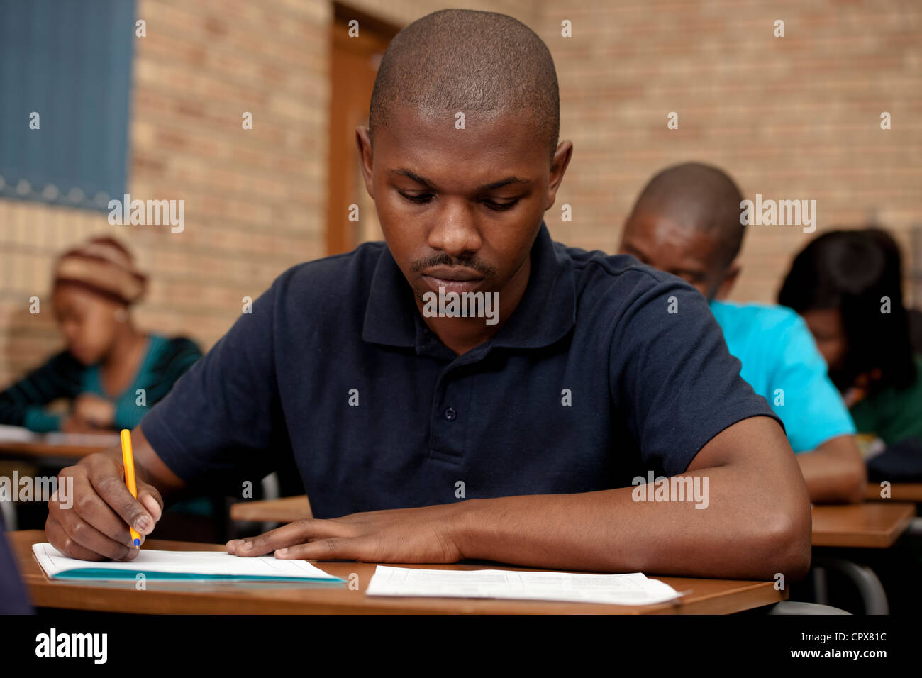 Male student working at a desk. Stock Photo