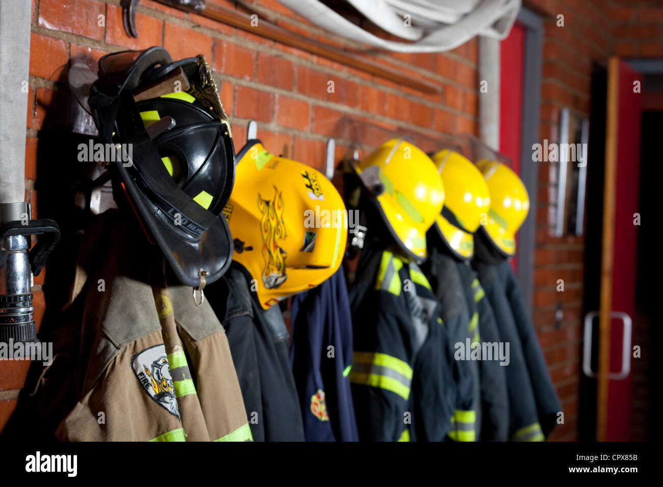 Firemen uniforms hanging up on a wall Stock Photo