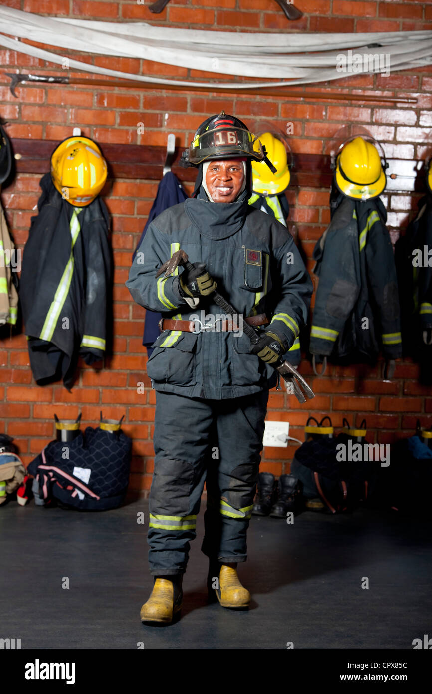 A Firemen posing with his kit and crowbar, smiling Stock Photo
